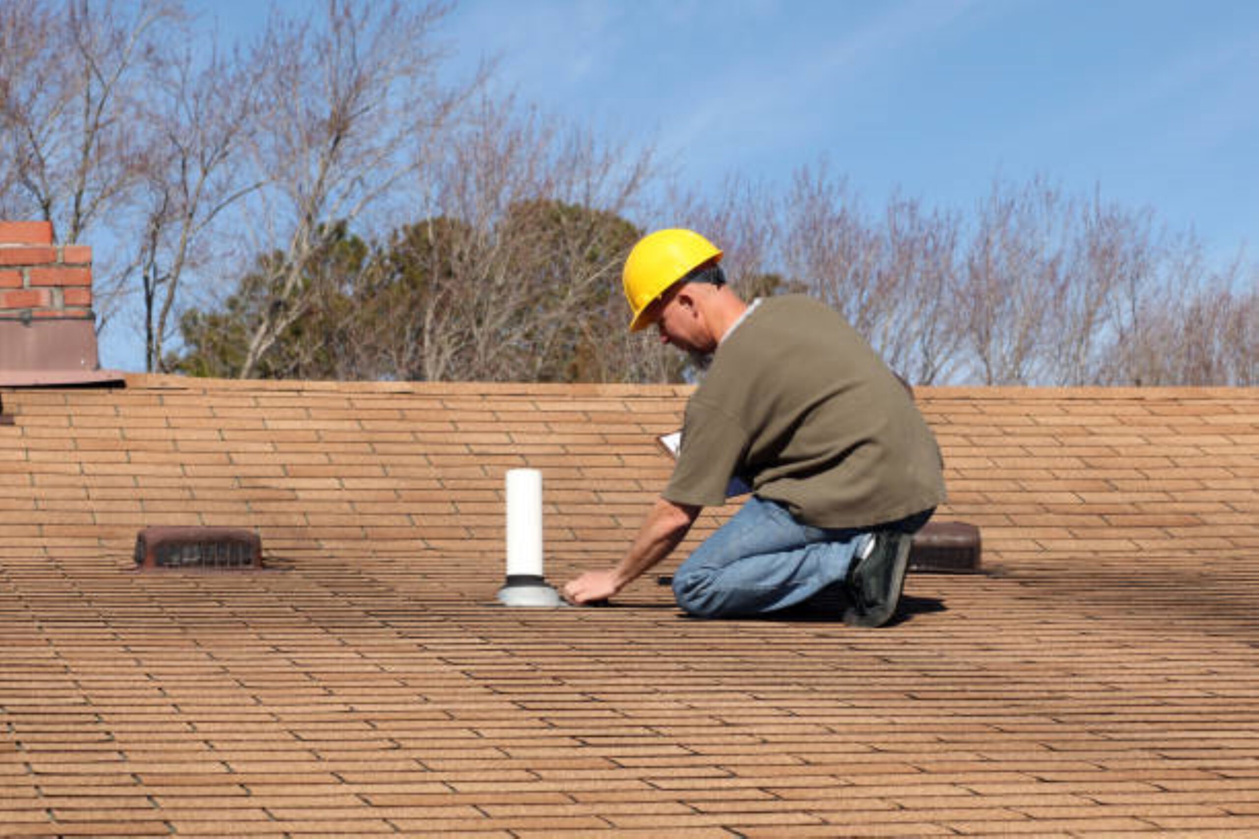 A man kneeling down on the roof of a building.